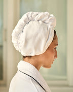 Woman wearing a white towel on her head in a neutral setting