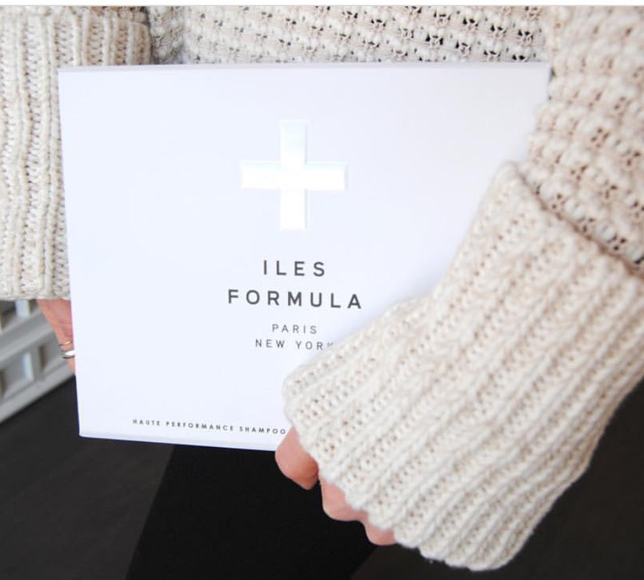 Person holding a white product packaging with text and a cross symbol.