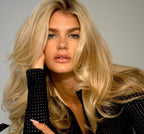 Woman with long, wavy blonde hair wearing a black polka dot shirt.