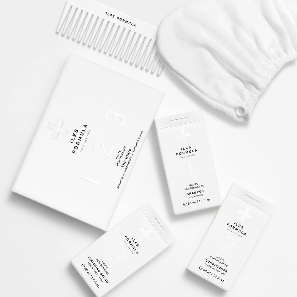 Limited Edition Travel Edit Flat Lay; The Minis Box, Mini Shampoo, Mini Conditioner, Mini Finishing Serum, Conditioning Distribution Comb, and Hair Turban Towel