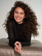 Woman with curly hair smiling on a neutral background