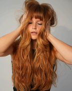 Woman with long, wavy red hair against a plain background