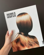 Book titled 'Archive II' by Wendy Iles held by a hand with a cover featuring a woman's head with styled hair.